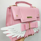 Sac à Main Rose Pâle à Ailes Blanches et Nœud Doré
